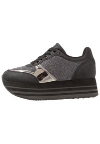 Mustat platform-tennarit, joissa on teksturoitu päällinen, metalliset yksityiskohdat ja kuvioitu sivupaneeli. Varustettu pyöreillä nauhoilla ja paksulla raidallisella pohjalla.