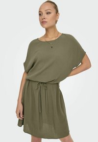 Khakifarbenes Kurzarmkleid aus leichtem, strukturiertem Stoff. Mit rundem Ausschnitt und einer taillierten Taille mit einer Bindegürteldetail.
