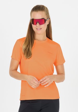 Lys orange atletisk t-shirt med korte ærmer, glat tekstur og rund halsudskæring. Sorte leggings og lyserødt solbriller fuldender looket.