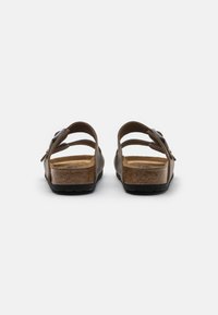Braune Plateausandalen mit zwei verstellbaren Riemen, einem Korkfußbett und einer strukturierten Gummisohle, von hinten betrachtet.