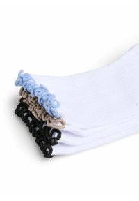 Pile de chaussettes blanches avec des poignets côtelés, chaque poignet présentant des boucles bouclées en bleu, beige et noir sur fond blanc.