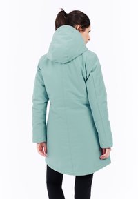 Ljus turkos huva kappa med lång skärning, som har en mjuk textur och minimalistisk design. Inga synliga knäppningar eller dekorationer.