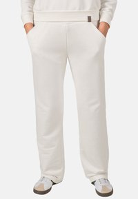 Lichtbeige sweatpants van zacht, ademend materiaal; voorzien van zijzakken en een subtiele logopatch; rechte pijpen.