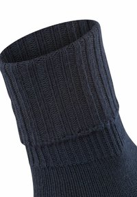 Calzino blu scuro con una texture a coste, dotato di un risvolto. Realizzato in un morbido tessuto lavorato a maglia, ha un finish liscio in tutta la sua estensione.