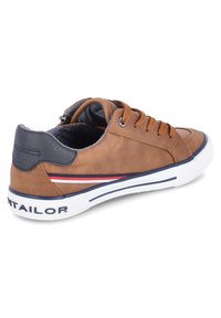 Sneaker beige a metà caviglia con patch blu sulla parte posteriore, lacci marroni, suola bianca con striscia blu, e strisce laterali rosse, bianche e blu, angolata a sinistra.