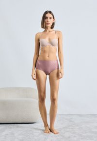 Lys pink bh med glatte skåle og justerbare stropper, parret med højtaljede, metallisk rosenfarvede trusser, begge lavet af blødt stof.