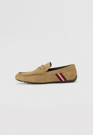 Brown suede loafer with a flat sole, featuring a woven strap and a side accent in red and black stripes. Smooth texture and simple design.