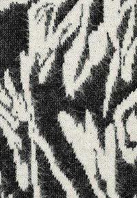 Schwarz-weißes Strickgewebe mit flauschiger Textur, das abstrakte Muster zeigt, die an Laub erinnern. Das Design umfasst verschiedene Formen und Umrisse.