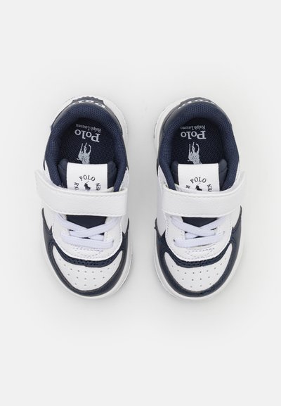 Sneaker per bambini bianche e blu navy, con cinturino in velcro, materiali in tessuto e sintetico, dettagli perforati e marchio sulla linguetta.