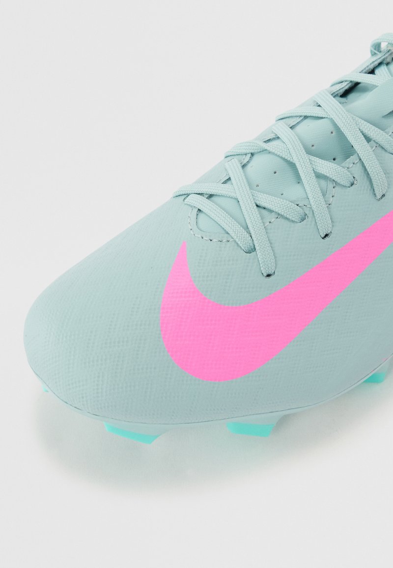 Jasnoniebieskie buty piłkarskie z teksturowaną cholewką, z wyraźnym różowym logo Nike oraz jasnoniebieskimi akcentami na podeszwie i sznurówkach.