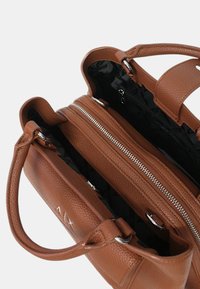 Borsa a tracolla in pelle marrone con finitura testurizzata, dotata di un compartimento con zip e dettagli in metallo argentato. Interno foderato in tessuto scuro.