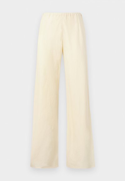 Vide benbukser i lys gul bomull. Har en elastisk midje og jevn tekstur, uten synlige lommer eller dekorasjoner.