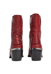 Botas de tobillo de cuero rojo con un acabado texturizado, que presentan un acento en el tacón plateado y un detalle con el logo en la parte posterior. Punta redondeada y diseño estilizado.