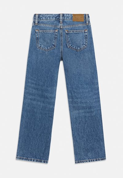 Μπλε τζιν παντελόνι κανονικής γραμμής, εμφανίζεται από πίσω με δύο τσέπες εφαρμοσμένες, δερμάτινη ετικέτα μάρκας στη μέση και θηλιές για ζώνη.