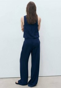 Marineblaues, lässiges Zweiteiler-Outfit aus leichtem Stoff; ärmelloses Top und weite Hosen mit Seitentaschen.