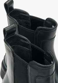 Černé kotníkové boty vyrobené z kůže a textilu s hladkým povrchem, elastickými bočními panely a poutky pro snadné obutí.