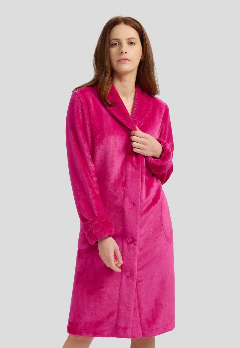Bata de baño de forro polar en un vibrante color rosa con cuello chal, cierre de botones en la parte delantera y dos bolsillos laterales; presenta una textura suave y mangas de largo completo.