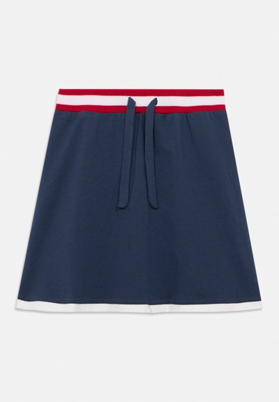 Jupe en coton bleu marine avec une taille élastique rayée rouge et blanche, dotée d'un cordon de serrage et d'un ourlet blanc en accent. Texture douce et coupe évasée.