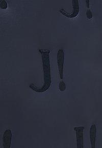 Marineblauw textiel met een structuur, versierd met geborduurde donkere letters "J" en uitroeptekens. Het ontwerp is uniform met een gladde afwerking.