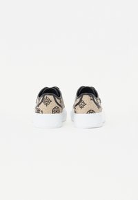 Tenisky s béžovým vzorovaným plátnem s černými designy, bílými gumovými podrážkami a černými akcenty na patě a límci.