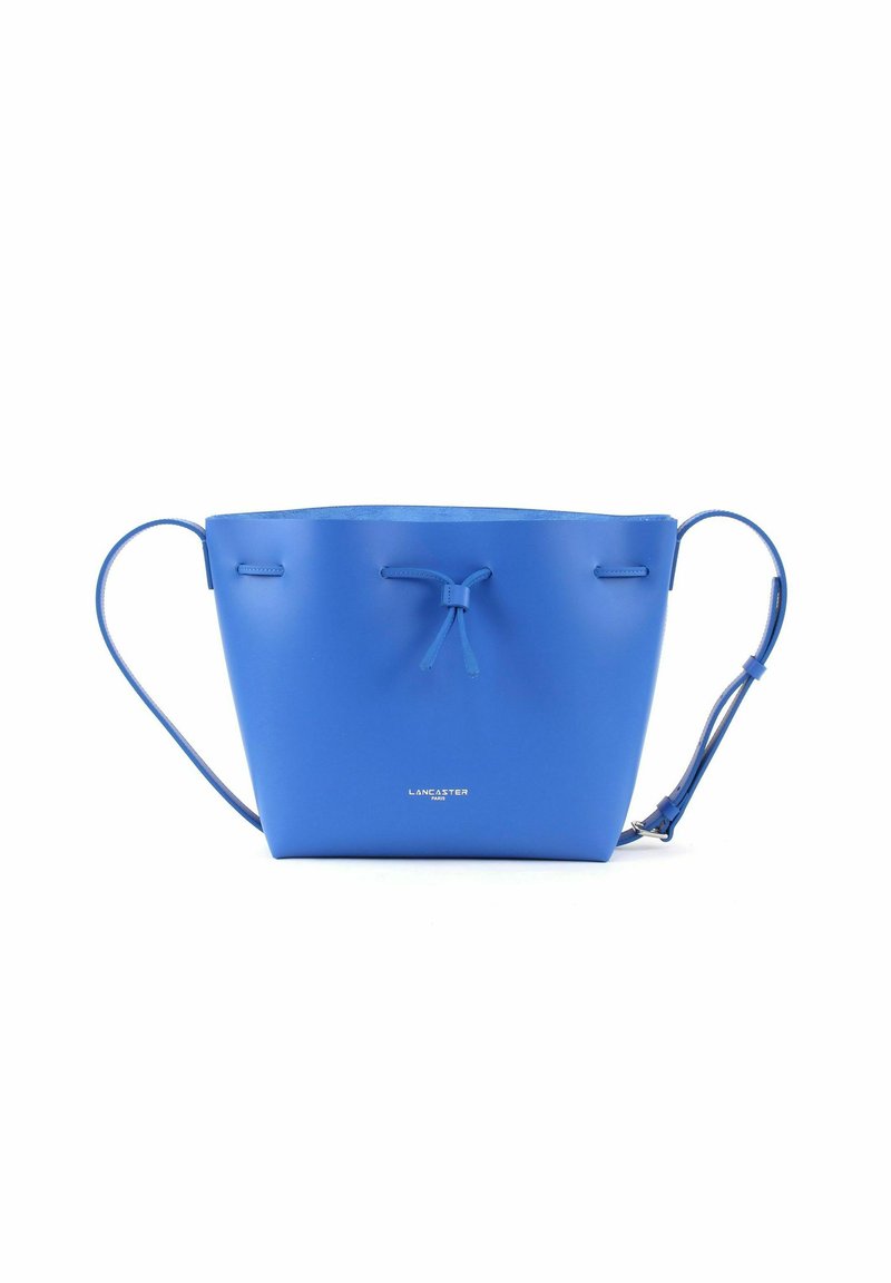 Sac seau en cuir bleu avec une forme ronde, de fines bandoulières et une fermeture à cordon. Il présente un logo en relief blanc sur le devant.