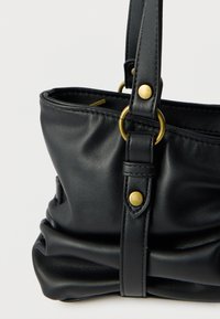 Sac à main en cuir noir à la forme structurée, présentant une texture froncée, des accents en métal doré et une bandoulière réglable.