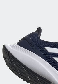 Gros plan d'une basket Adidas bleu marine mettant en avant le talon, la semelle intermédiaire blanche et la semelle extérieure noire texturée.