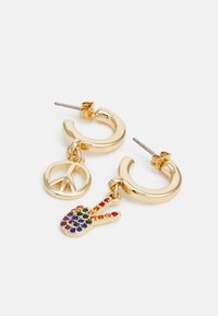 Brincos de argola dourada com um símbolo da paz e um encantamento de gesto de mão colorido adornado com gemas. Os encantos estão ligados por uma corrente fina.
