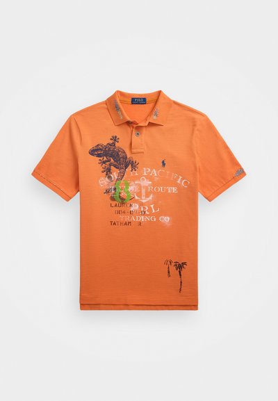 Oranžs polo krekls ar apkakli, ar dzīvnieku un palmu koku drukājumiem, izšuvumiem un teksta detaļām priekšā.