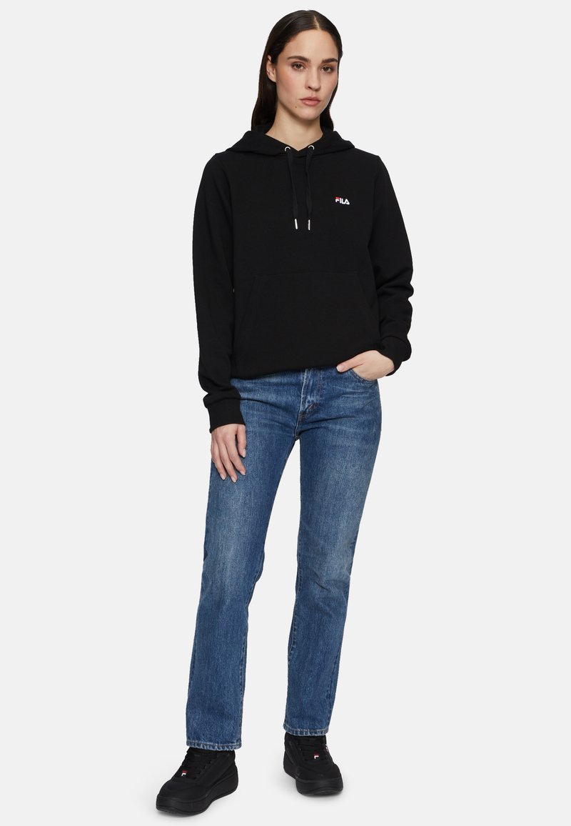 Felpa nera con cappuccio, coulisse e tasca anteriore, abbinata a jeans blu e sneakers nere. Presenta il logo Fila sul petto.