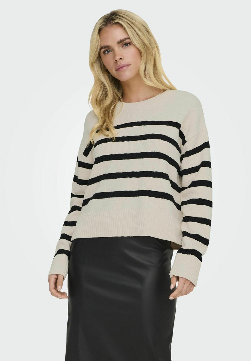 Gestreifter Pullover in Beige und Schwarz, mit Rundhalsausschnitt, lockerer Passform und gerippten Bündchen, kombiniert mit einem schwarzen Lederrock.