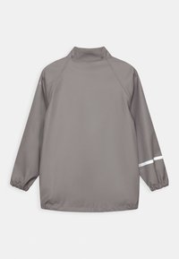 Grå vandtæt jakke med høj krave, lange ærmer, elastiske manchetter og en hvid reflekterende stribe på hver ærme. Glat tekstur.