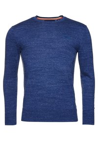 Pitkähihaisen sinisen neulepaidat, jossa on pyöreä pääntie, huomaamaton tekstuuri ja pieni logo rinnassa. Sisäkauluksen yksityiskohdat ovat kontrastiväriset.