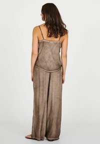 Piesa vestimentară în două piese, de culoare maro, cu o croială lejeră, confecționată dintr-un material moale și texturat; bretele tip spaghetti și pantaloni evazați; design simplu și modest.
