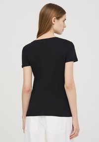 T-shirt nero a maniche corte con scollo rotondo, caratterizzato da una silhouette aderente e un materiale jersey liscio.
