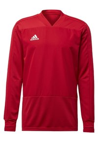 Maillot de sport rouge à manches longues en tissu respirant, avec un col en V, une surface texturée et trois bandes blanches sur les épaules.