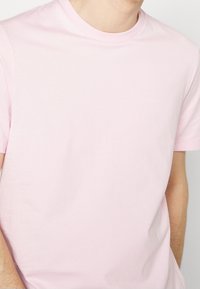 Light pink cotton t-shirt with a crew neckline, short sleeves, and a subtle embossed "Boss" logo on the left chest. Smooth texture.