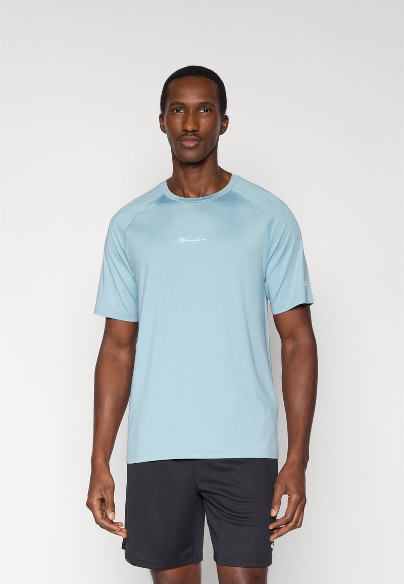 Ανοιχτό μπλε αθλητικό μπλουζάκι από διαπνέον ύφασμα, με κοντά μανίκια, στρογγυλή λαιμόκοψη και μικρό λογότυπο στο στήθος.