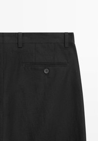 Pantalon formel noir avec passants pour ceinture et une seule poche arrière boutonnée sur le côté droit.