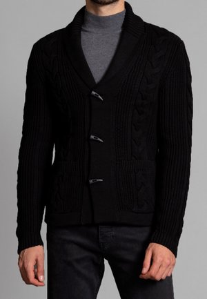 Sort strikket cardigan med sjalskrave, med kabelmønstre og tre lukke-knapper. Indeholder to for lommer.