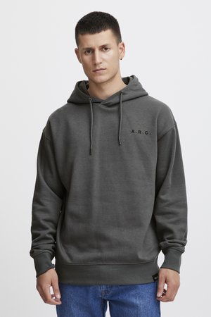 Mørkegrå hettegenser laget av mykt stoff, med snor i hetten og brodert "A.R.C." logo på brystet. Ribbestrikkede mansjetter og kant.