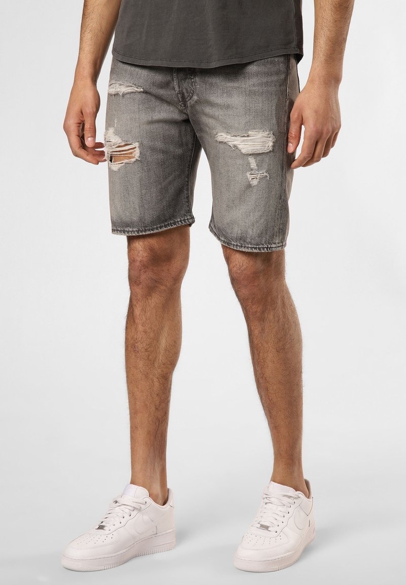 Shorts en jean gris avec détails usés, bords effilochés et coupe décontractée, associés à des baskets blanches.