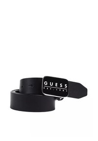Cinturón de cuero negro con una hebilla metálica rectangular que presenta el logotipo de "GUESS" y el texto "EST. 1981". Textura suave y diseño clásico.