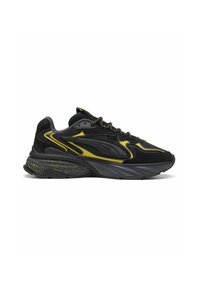 Baskets de sport noires et jaunes avec semelle épaisse, talon moucheté, dessus en mesh et daim, lacets à motifs, vues de profil.
