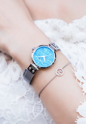 Silbernes Netzarmbanduhr mit einem runden blauen strukturierten Zifferblatt. Verfügt über silberne Stundenmarkierungen und Zeiger, zusammen mit einem filigranen silbernen Armband.