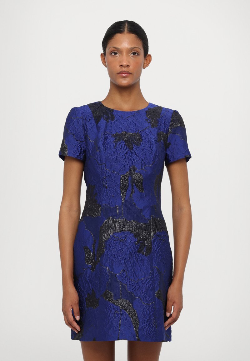 Zils ziedu kleita ar strukturētu audumu, īsām piedurknēm un pieguļošu siluetu ar melniem akcentiem un apaļu kakla izgriezumu.