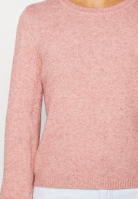 Hellrosa gestrickter Pullover mit rundem Ausschnitt und langen Ärmeln, der eine weiche Textur aufweist und einen Saum hat, der in der Taille sitzt.