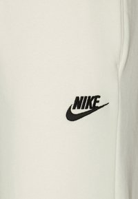 Primeira página de tecido branco com o logótipo Nike bordado a preto e o swoosh no lado direito.