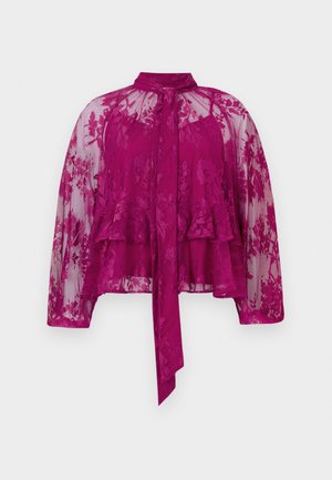 Bluză magenta din dantelă, cu mâneci lungi, din material transparent, broderie florală și guler legat. Are un design suprapus și o margine evazată.