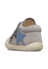 Zapato de ante gris con un acento de estrella azul, forma redondeada, parte superior texturizada y forro de cuero suave. Presenta una suela de goma flexible.